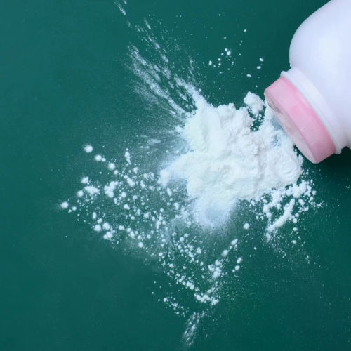 Baby talcum powder container spilling powder on a blue background