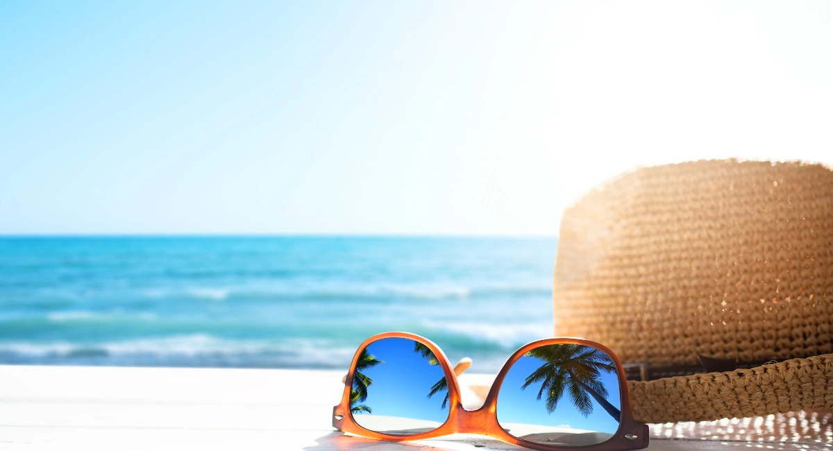 A pair of glasses and hat in front of beach