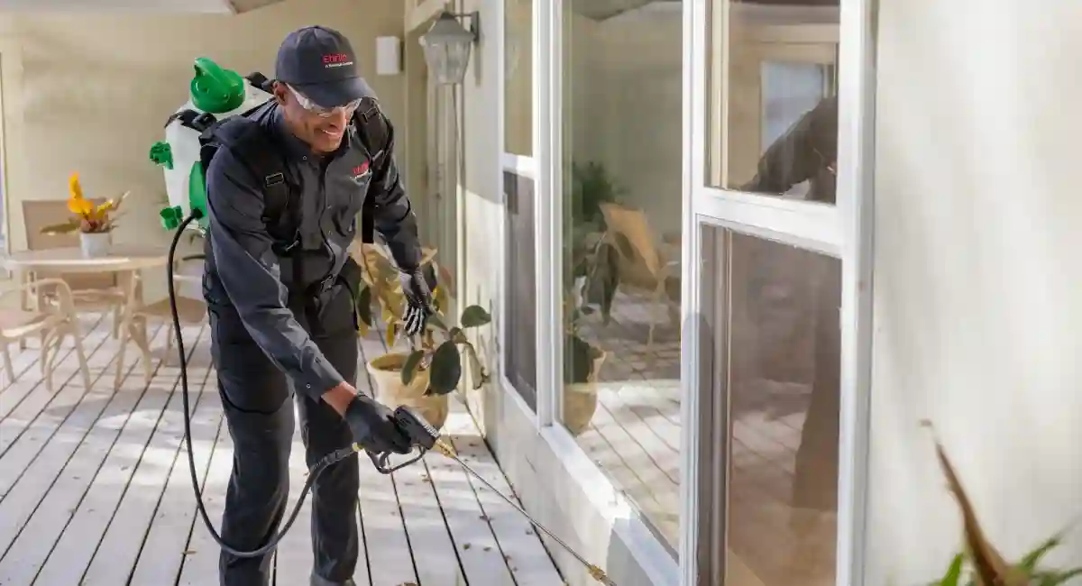 Technician spraying windows outside a home