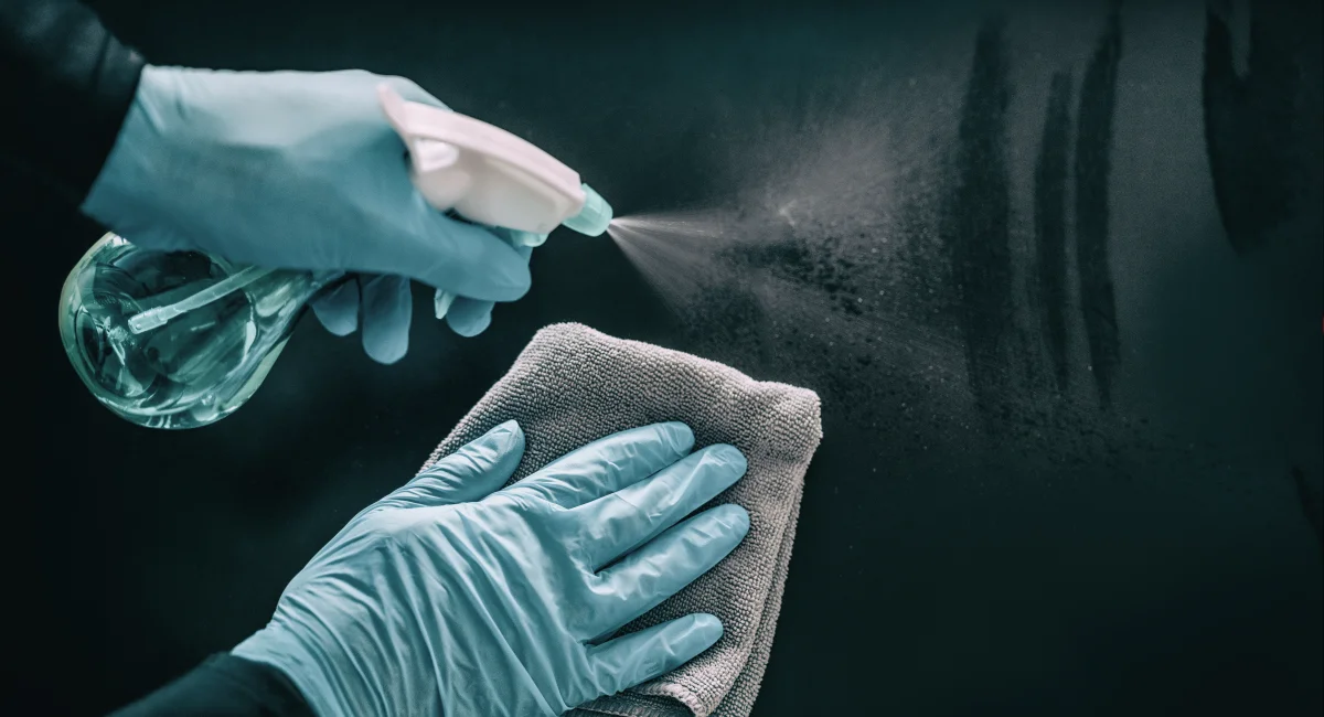 A person scrubs the floor, wearing gloves
