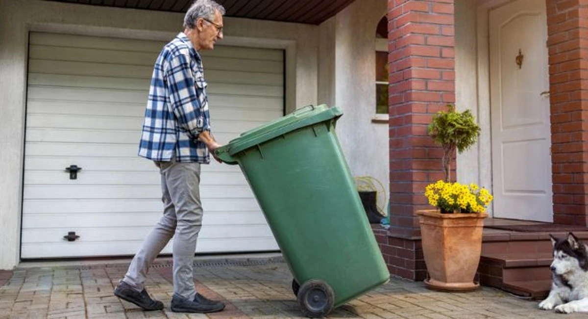 Elderly man putting bins out