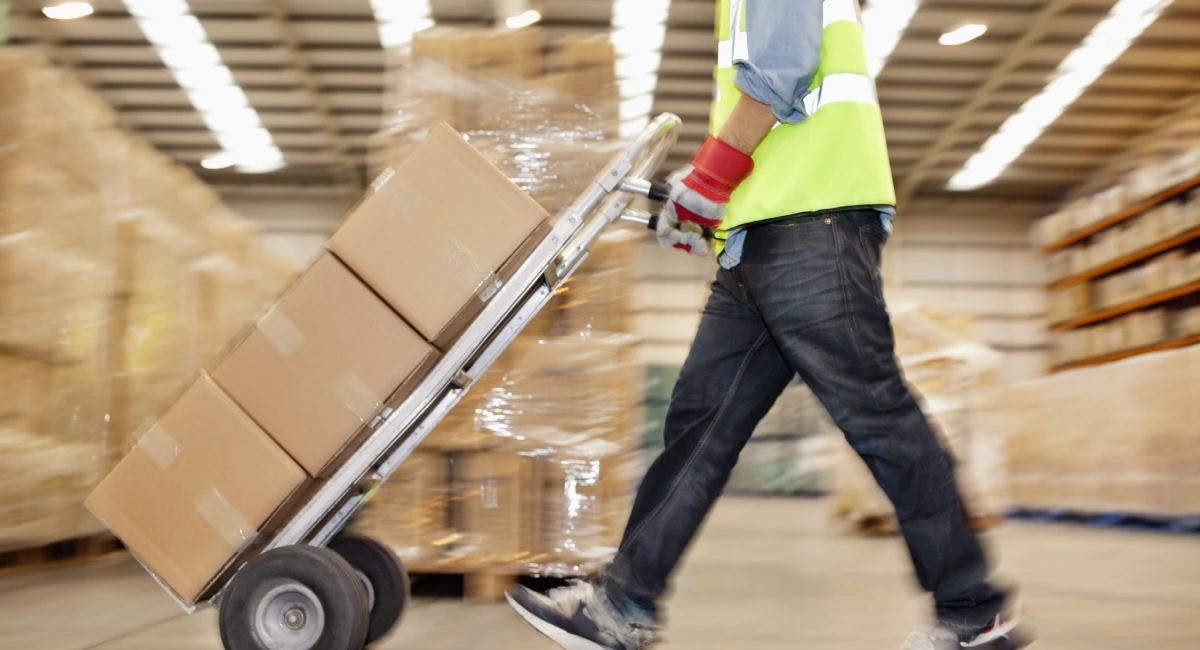 side-view-of-worker-pushing-trolley-of-cardboard