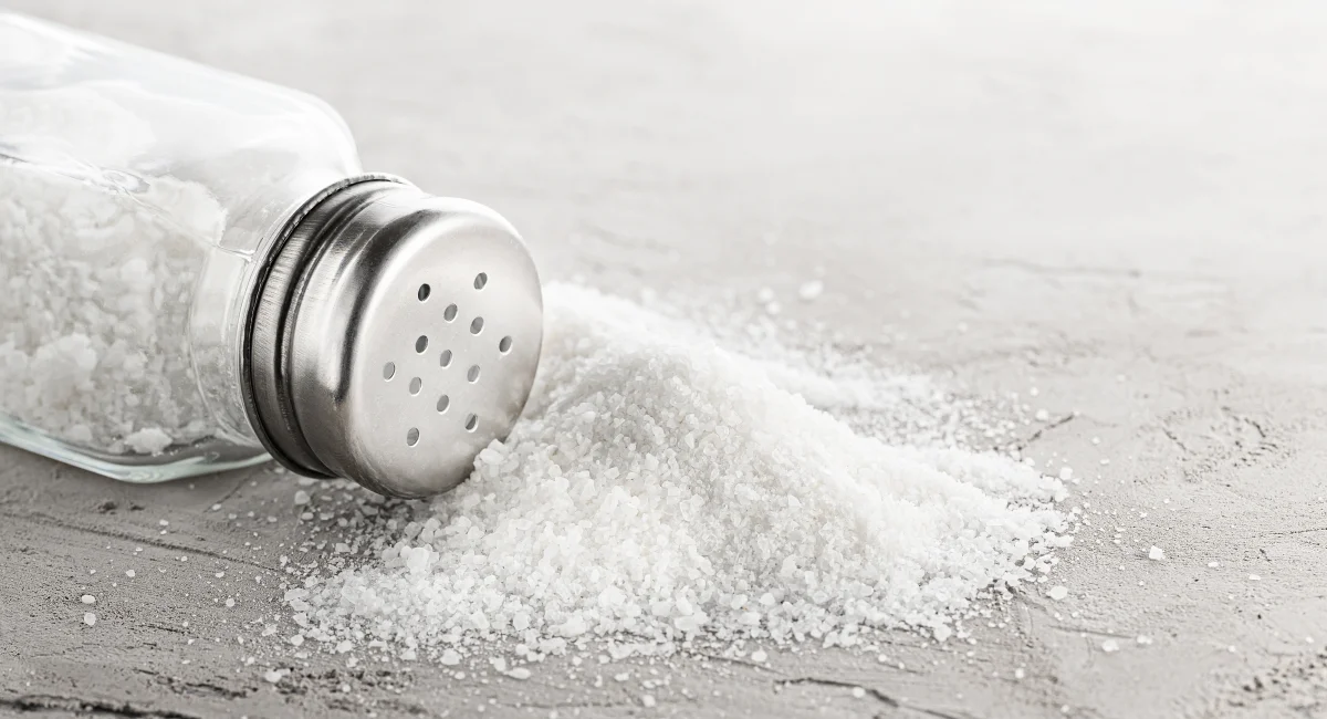 A fallen salt shaker spilling salt all over a countertop